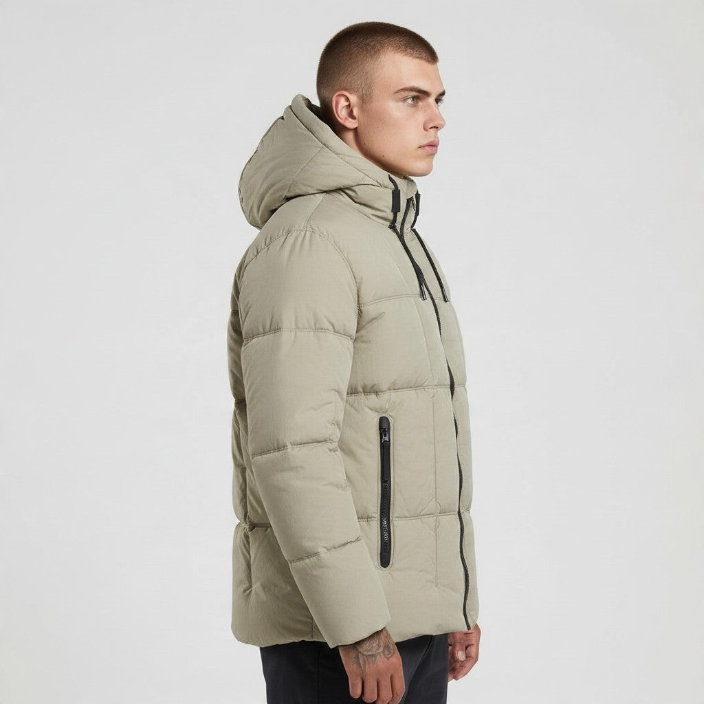 Homme portant une doudoune bonhomme beige à capuche, matelassage carré et fermetures zippées noires, vue de profil