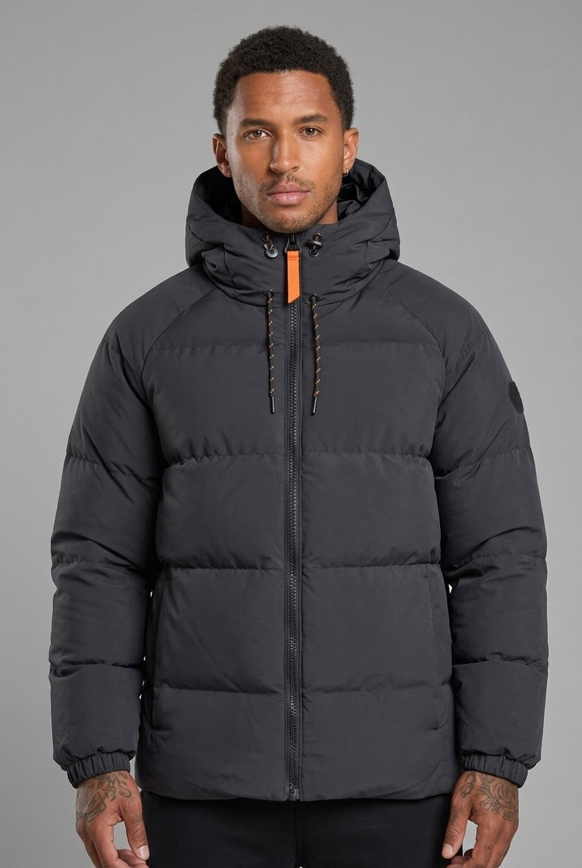 Homme portant une doudoune bonhomme noire matelassée à capuche avec détails orange sur les zips et cordons