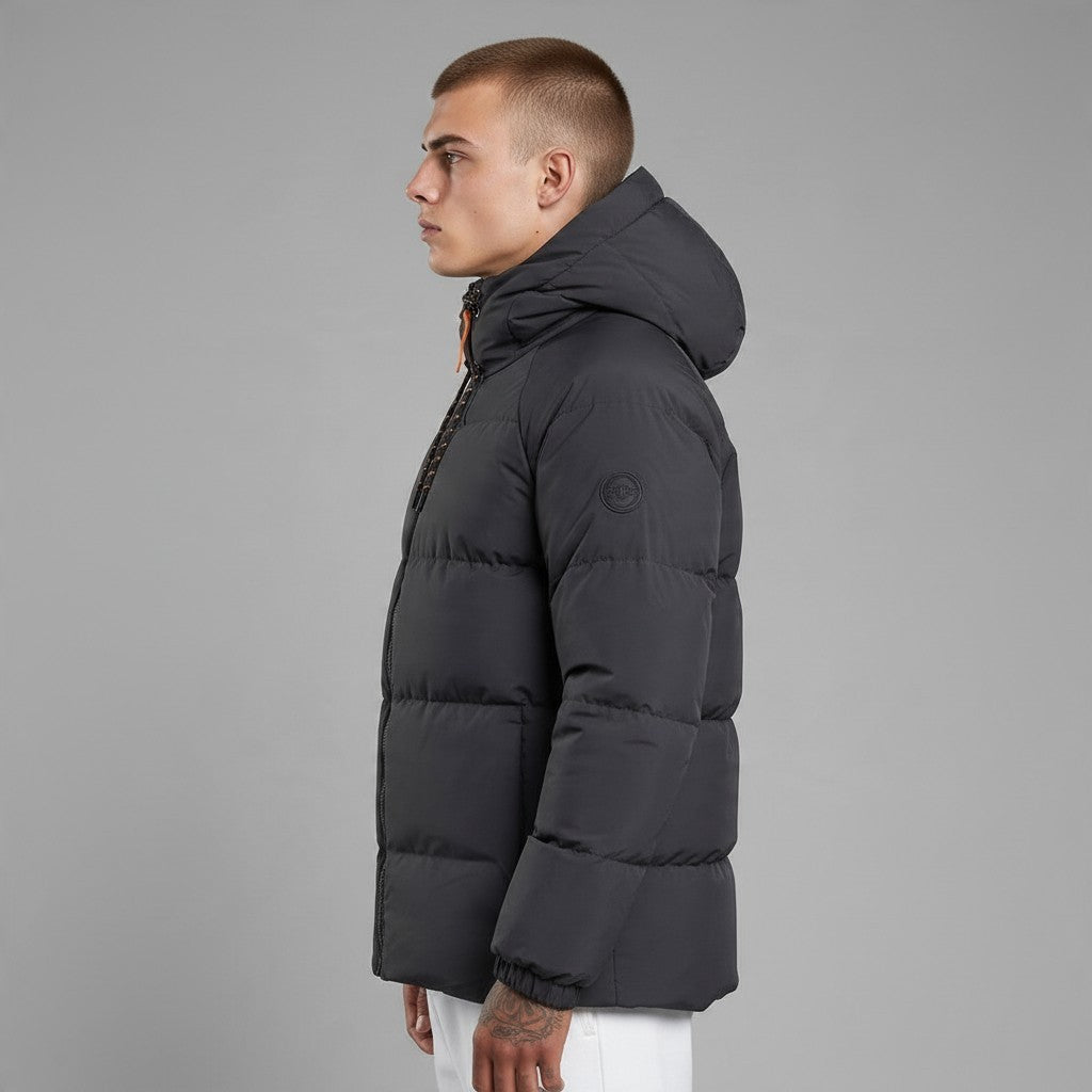 Homme portant une doudoune bonhomme noire matelassée à capuche avec détails orange, vue de profil sur fond gris