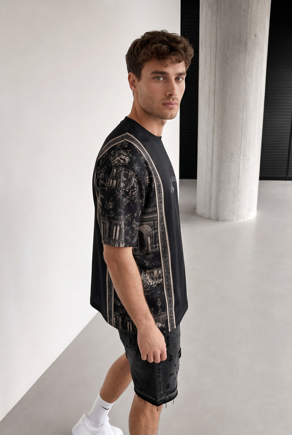 Homme portant un t-shirt noir bonhomme Club Paris en polyester et lycra avec imprimé architectural sur les manches