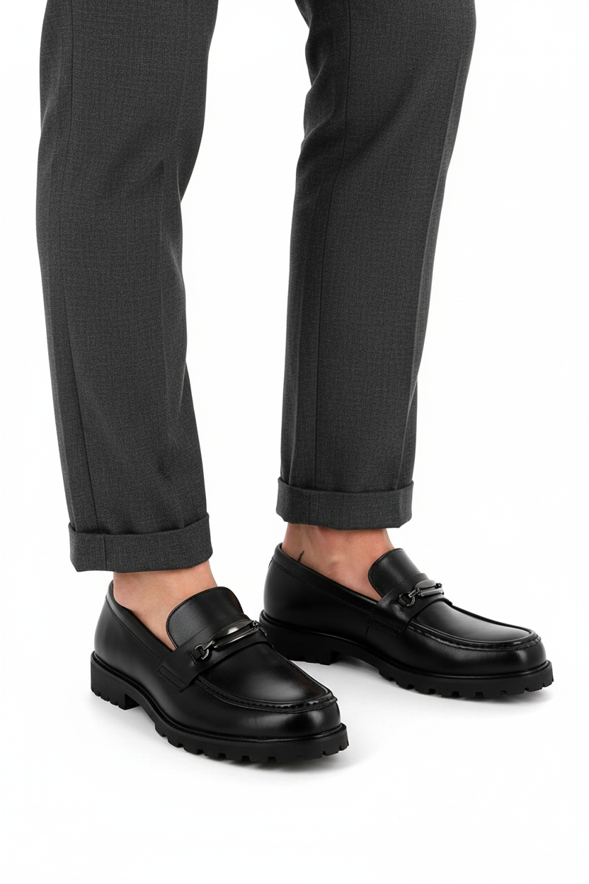 Mocassin Bonhomme noir à mors métallique et semelle épaisse crantée porté avec un pantalon gris